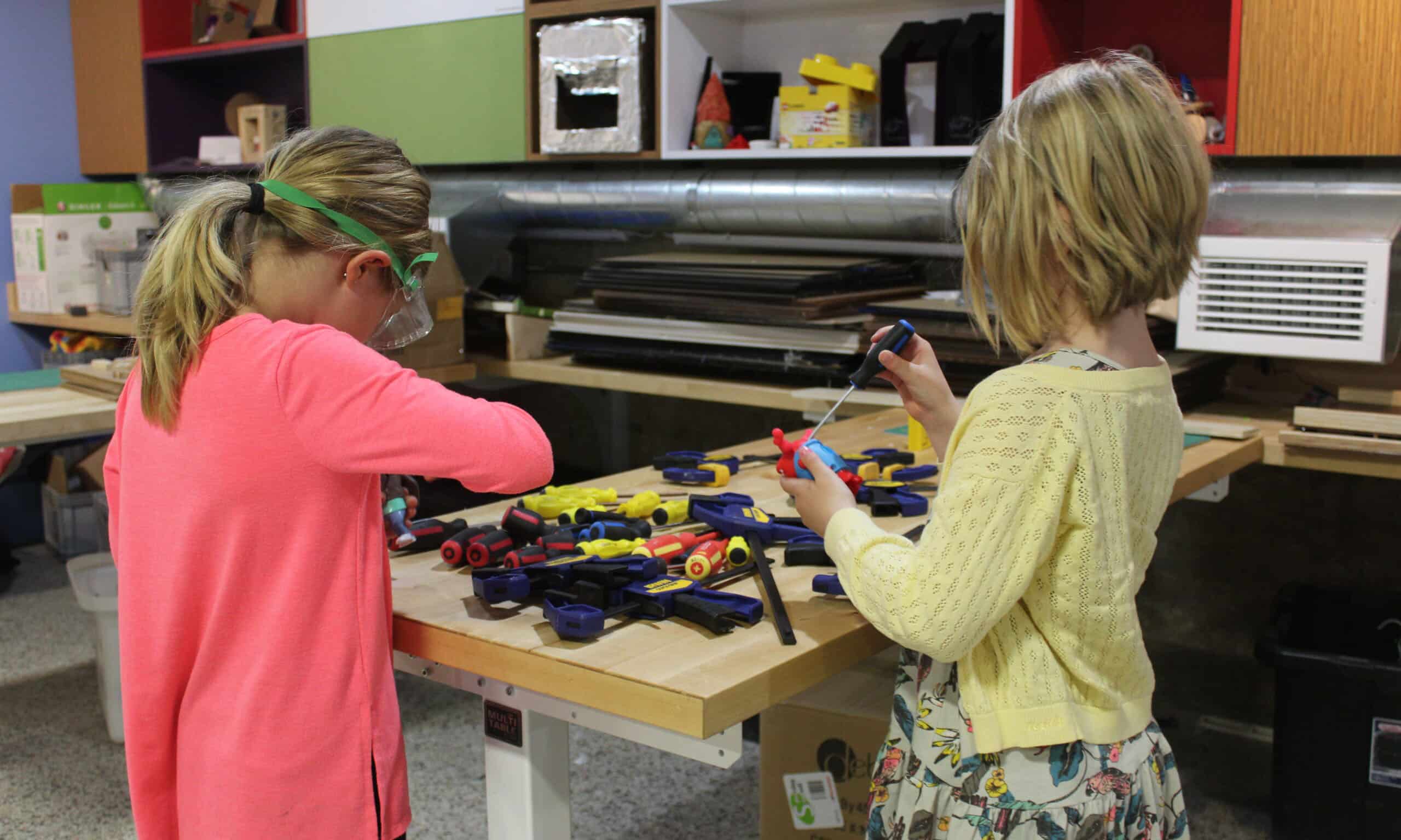 Two young people wearing safety goggles working with tools on a project